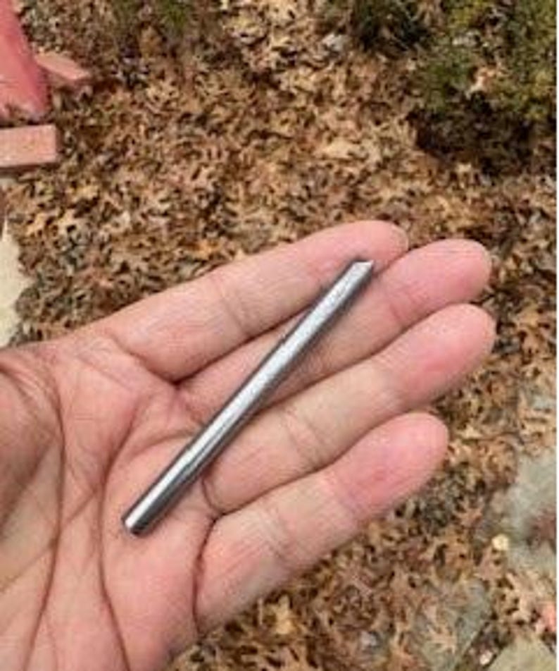 May include: A silver metal rod with a pointed tip. The rod is about 3 inches long.