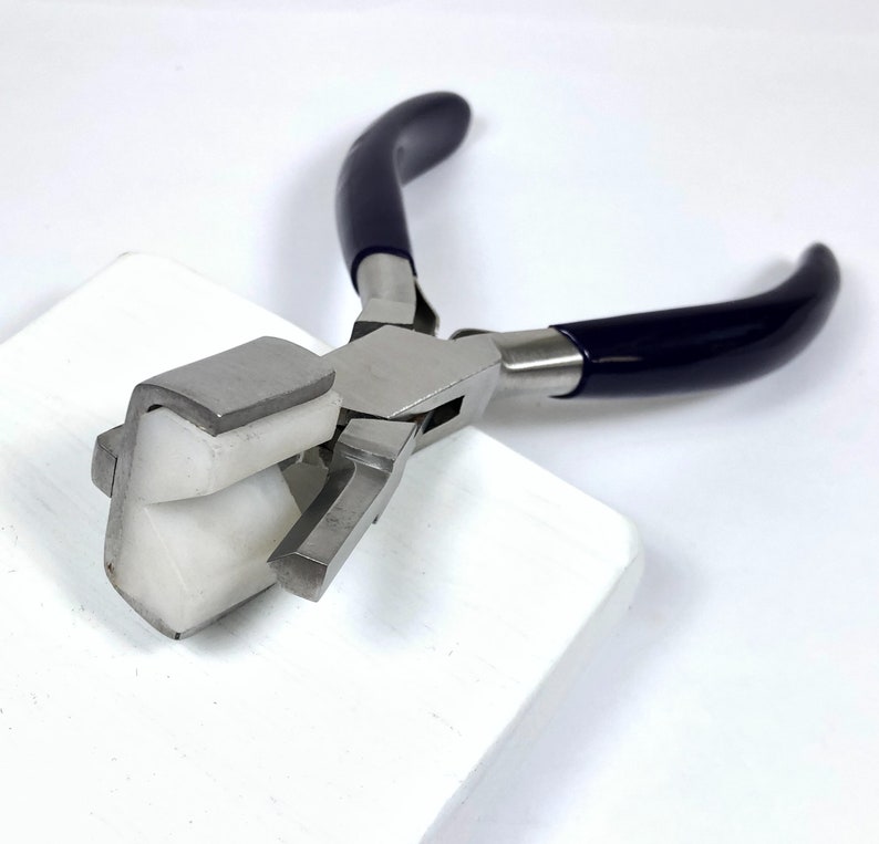 May include: A pair of metal pliers with dark blue handles and a white, angled jaw. The pliers are designed for jewelry making or crafting, with a focus on precision and detail work. The tool is set against a white background.