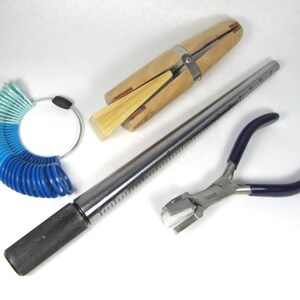 May include: A set of jewellery making tools including a ring mandrel, ring sizer, and a pair of pliers with a blue handle.