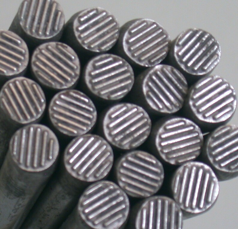 May include: A close-up of a group of silver metal rods with a textured, grid-like pattern on the top of each rod.
