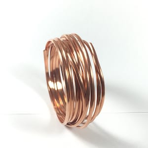 May include: A coil of copper wire, approximately 12 gauge, in a copper color. The wire is coiled and ready for crafting projects.
