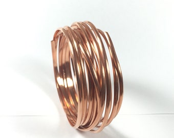 May include: A coil of copper wire, approximately 12 gauge, in a copper color. The wire is coiled and ready for crafting projects.