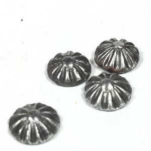May include: Four silver metal dome-shaped buttons with a decorative, radial pattern. The buttons have a slightly aged, tarnished look.