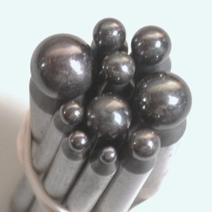 May include: A set of metal tools with round, silver-colored heads. The tools are bundled together and the heads are arranged in a cluster.
