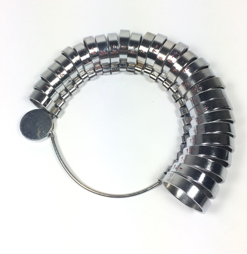 May include: A silver ring sizer with numbered rings from 1 to 17. The rings are attached to a metal loop.