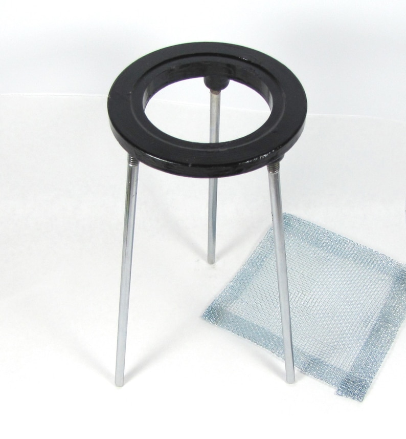 May include: A black metal ring stand with three legs and a wire mesh. The stand is used to support beakers and other laboratory equipment.
