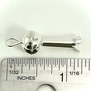 May include: Silver bead with a loop and a long, thin, pointed end. The bead is about 1/2 inch in diameter. The end is about 1 inch long.