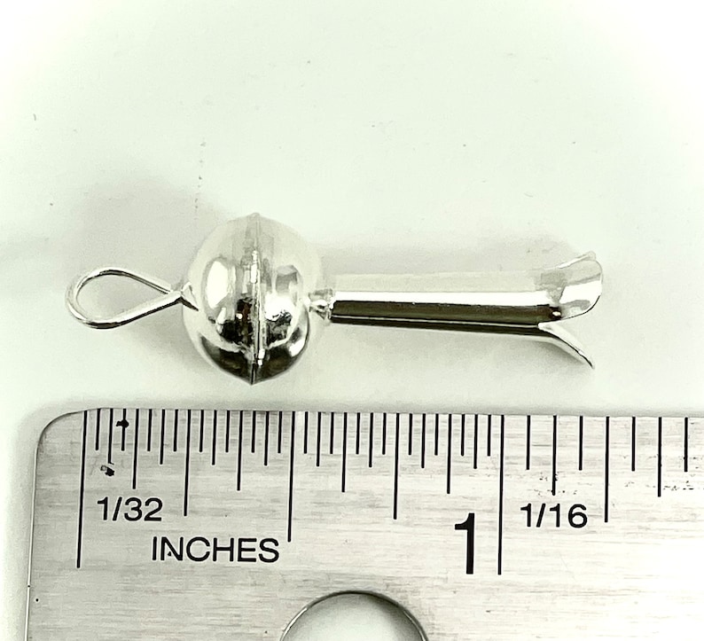 May include: Silver bead with a loop and a long, thin, pointed end. The bead is about 1/2 inch in diameter. The end is about 1 inch long.