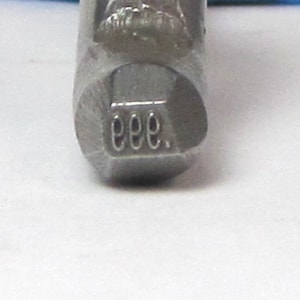 May include: Close-up of a metal tool with a hexagonal head. The tool is marked with the letters "EEE."