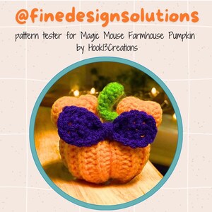 May include: A crocheted pumpkin with a purple bow and green stem. The pumpkin is orange and the bow is a dark purple. The stem is a bright green. The pumpkin is sitting on a wooden surface. The text "pattern tester for Magic Mouse Farmhouse Pumpkin by Hookl3Creations" is above the pumpkin.