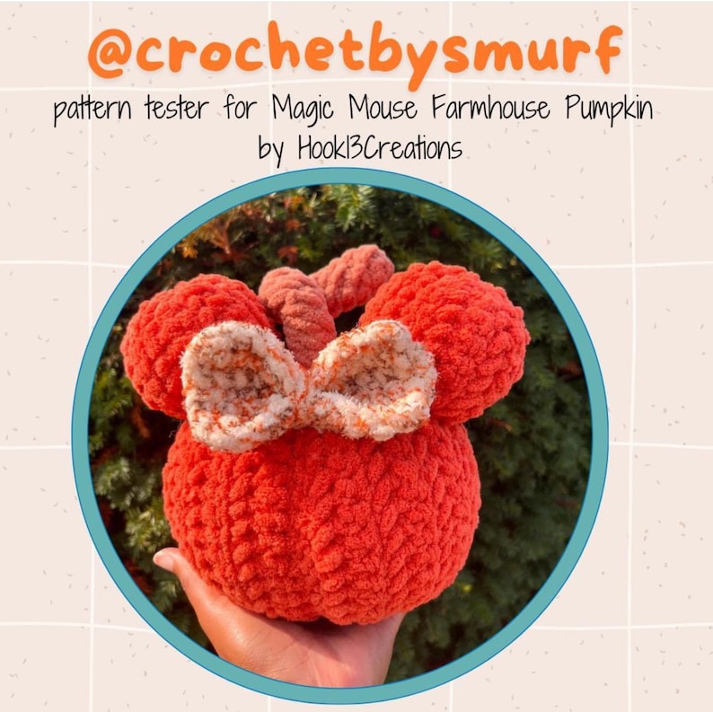 May include: A crocheted pumpkin shaped like Mickey Mouse with a bow. The pumpkin is orange and the bow is white and orange. The text "@crochetbysmurf pattern tester for Magic Mouse Farmhouse Pumpkin by Hookl3Creations" is above the pumpkin.