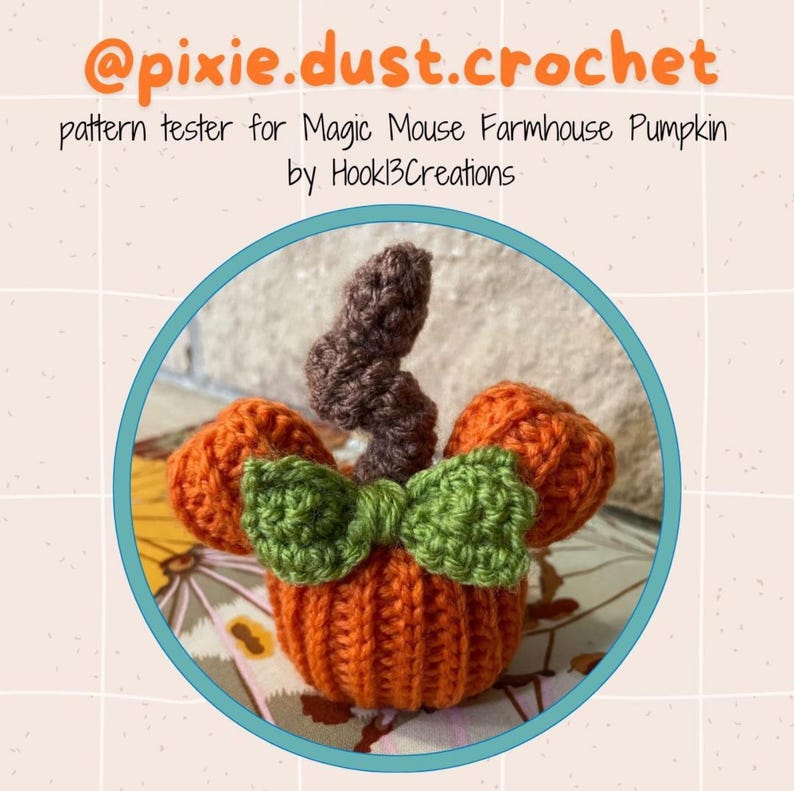 May include: A crocheted pumpkin with a brown stem and a green bow. The pumpkin is orange and has a Mickey Mouse ear shape. The text "@pixie.dust.crochet pattern tester for Magic Mouse Farmhouse Pumpkin by Hookl3Creations" is visible in the image.