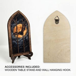 May include: A pointed arch wooden frame featuring a gothic window design with a printed image of a bat flying in front of a full moon. The set includes a detachable wooden table stand and a metal wall hanging hook attached to the back panel.