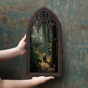 May include: A dark brown wooden frame with a pointed gothic arch top containing a decorative trefoil cutout. The frame displays a printed image of a figure in a long cloak walking along a path through a dense forest with tall trees.