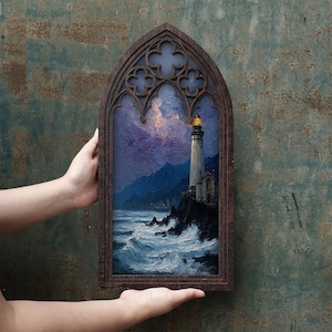 May include: A rectangular wall art piece featuring a painting of a lighthouse on a rocky cliff overlooking a turbulent ocean at night, framed in dark wood with a gothic-style arched top containing decorative quatrefoil cutouts.