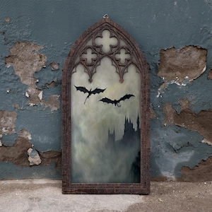 May include: A tall, arched wall hanging featuring a dark brown, textured frame with gothic tracery at the top. The central panel depicts a misty, atmospheric scene with two black dragon silhouettes flying above a dark, jagged castle silhouette.