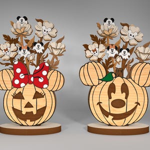 Puede incluir: Dos decoraciones de calabaza de Halloween de madera con orejas de Mickey Mouse y Minnie Mouse. Las calabazas tienen caras talladas y están decoradas con flores y pequeñas figuras de Mickey Mouse.