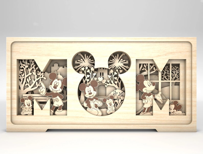 May include: Wooden box with a cutout design of the word "MUM" featuring Mickey Mouse and Minnie Mouse characters. The box is light brown and has a natural wood finish.