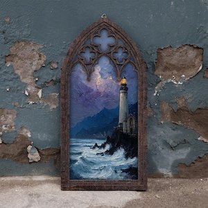 May include: A rectangular wall art piece featuring an oil painting of a lighthouse on a rocky cliffside at night, set within a dark brown wooden frame with a pointed gothic arch top and decorative quatrefoil cutouts at the upper section.