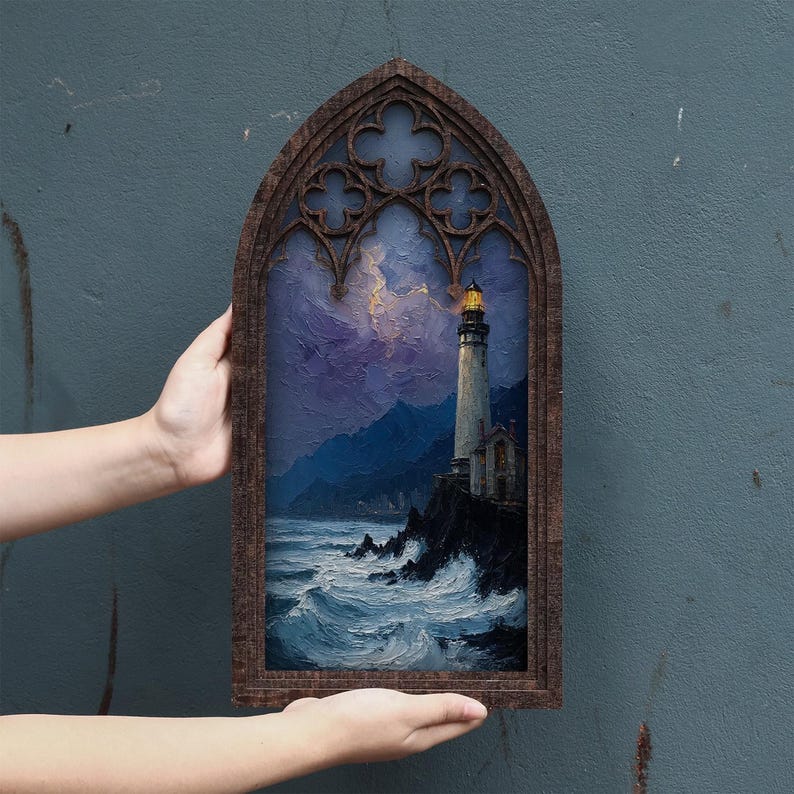 May include: A rectangular wall art piece featuring a painting of a lighthouse on a rocky cliffside at night, set within a dark brown wooden frame with a pointed gothic arch top. The painting depicts crashing ocean waves and a stormy purple sky.