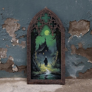 May include: A gothic-style arched wooden frame containing a print of a dark, misty forest scene. The image features a lone figure in a cloak walking toward a house under a bright green moon, surrounded by gnarled trees and a small stream.