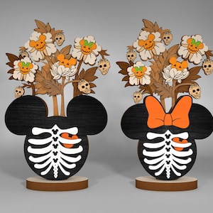 May include: Two wooden Halloween decorations featuring Mickey Mouse and Minnie Mouse with skeletons and pumpkins. The decorations are painted black, white, orange, and brown.