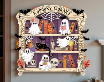 Puede incluir: Estantería de madera con temática de Halloween con el texto "A Spooky Library". La estantería está decorada con fantasmas, libros, un gato negro, murciélagos, telarañas, velas y calaveras. Los estantes son morados y el marco es marrón claro.