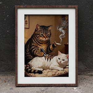 May include: A framed wall art print depicting a brown tabby cat holding a tattoo machine and a lit cigarette while tattooing a white cat with dark stripes. The scene is set in a room with warm lighting, and the artwork is encased in a dark wood frame.
