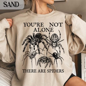 Crewneck sweatshirt with multiple spider illustrations and text.