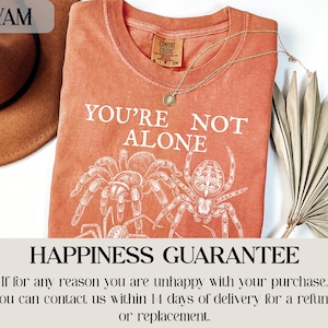 Orange t-shirt with "YOU'RE NOT ALONE" and spider graphic.