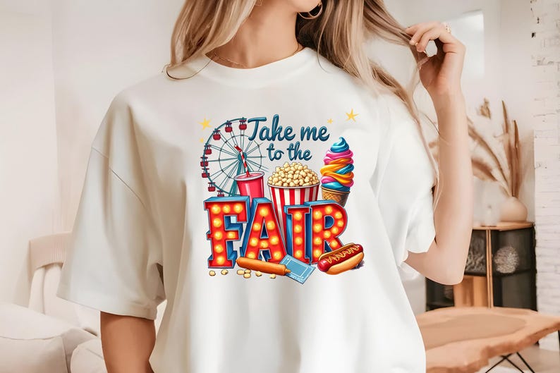 May include: White t-shirt with a colorful graphic design that says "Take me to the Fair". The graphic includes a Ferris wheel, popcorn, ice cream, and a hot dog.