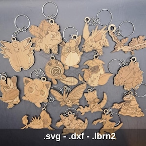 Könnte beinhalten: Ein Set mit 15 Holzschlüsselanhängern mit verschiedenen Pokémon-Charakteren. Die Schlüsselanhänger sind lasergeschnitten und haben eine natürliche Holzoptik. Zu den Charakteren gehören Bisasam, Glumanda, Schiggy, Pikachu und viele mehr.