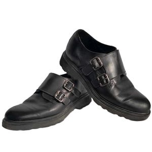 May include: A pair of black leather shoes with double buckles. The shoes have a chunky sole and a rounded toe.