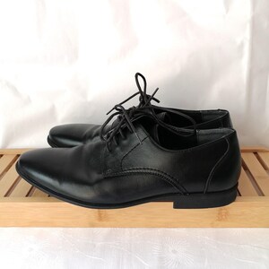 May include: A pair of black leather lace-up shoes with a rounded toe.