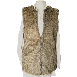 May include: A brown faux fur vest with a vertical design. The vest is displayed on a white shirt and mannequin. The vest has a V-neck and a soft, textured appearance. The vest is sleeveless.
