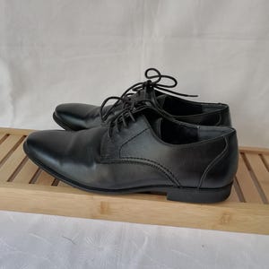 May include: A pair of black leather lace-up dress shoes. The shoes have a classic design and are in good condition.