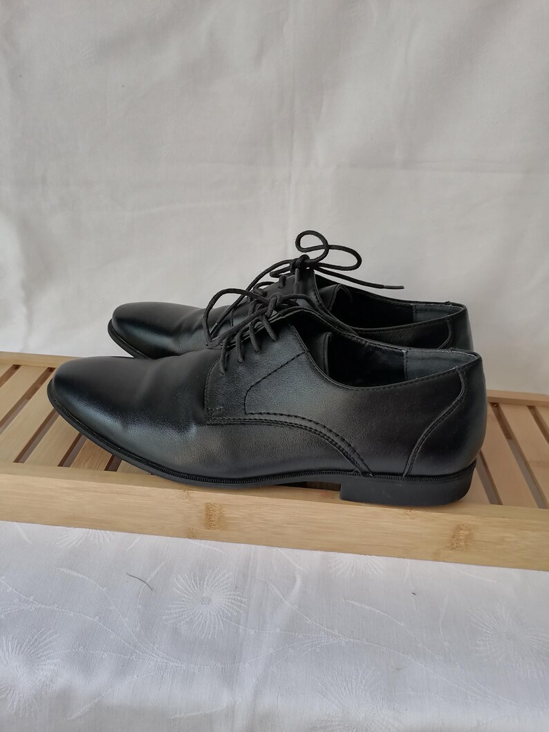 May include: A pair of black leather lace-up dress shoes. The shoes have a classic design and are in good condition.