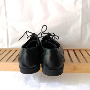 May include: A pair of black leather lace-up shoes with a rounded toe and a thick sole.