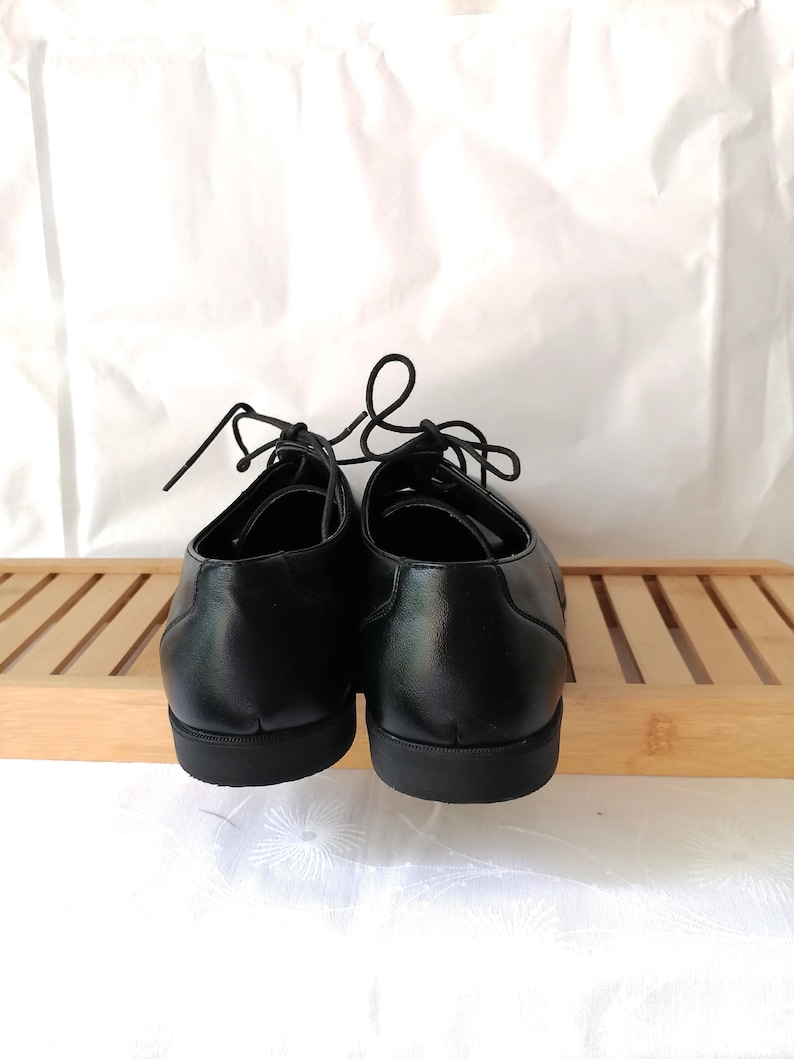 May include: A pair of black leather lace-up shoes with a rounded toe and a thick sole.
