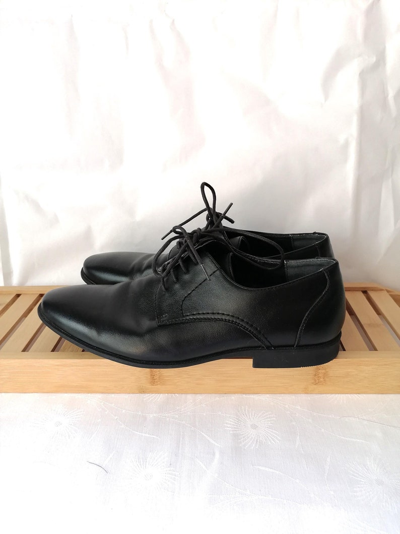 May include: A pair of black leather lace-up shoes with a rounded toe.