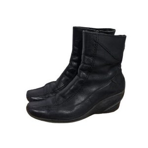 May include: Black leather ankle boots with a wedge heel. The boots have a zip on the inside of the ankle.