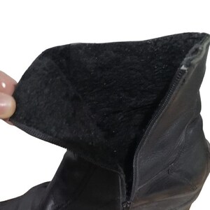 May include: Black leather ankle boots with a side zip and a soft, black lining. The boots have a rounded toe and a low heel.