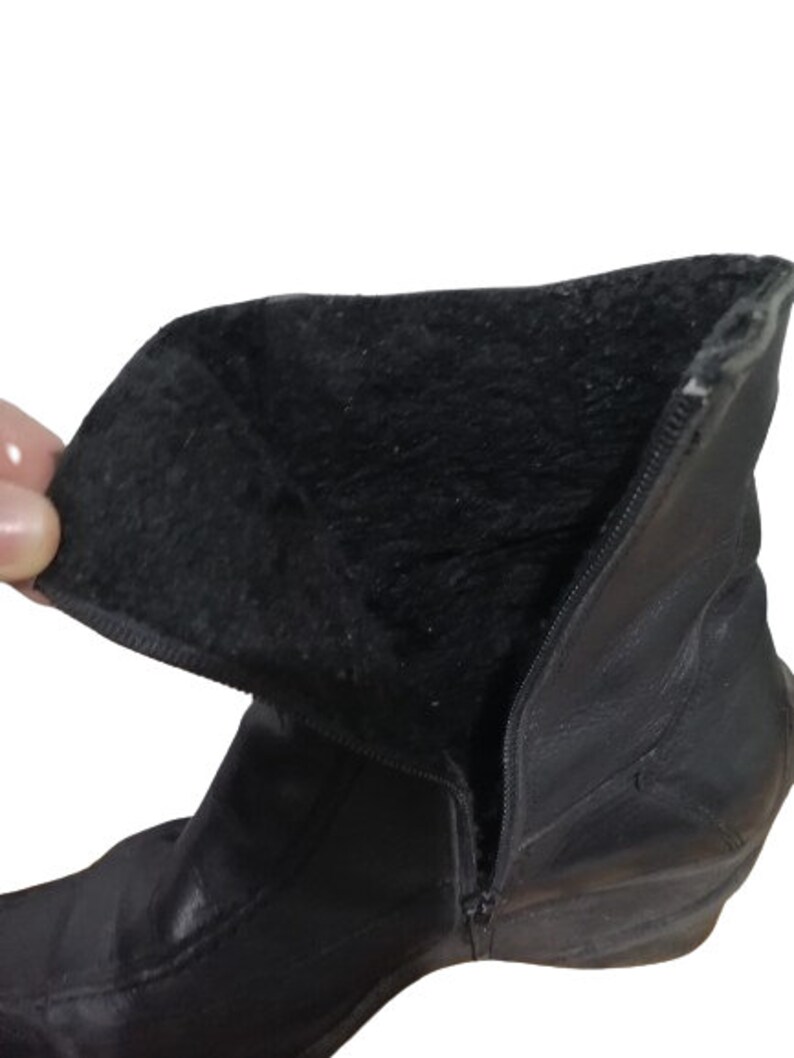 May include: Black leather ankle boots with a side zip and a soft, black lining. The boots have a rounded toe and a low heel.