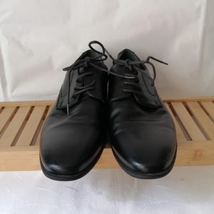 May include: A pair of black leather lace-up shoes. The shoes have a classic design and are in good condition.