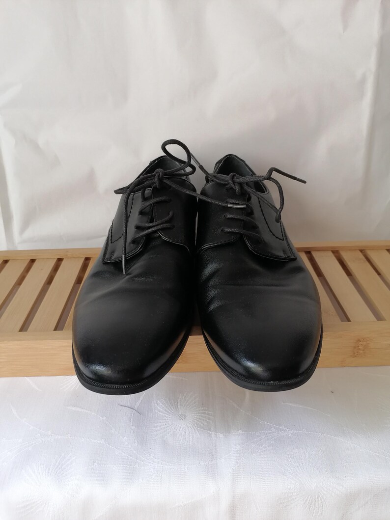 May include: A pair of black leather lace-up shoes. The shoes have a classic design and are in good condition.