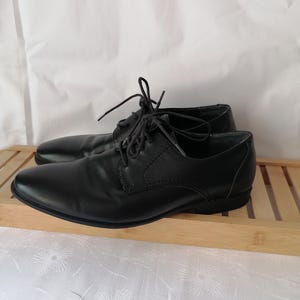 May include: A pair of black leather lace-up shoes with a classic design. The shoes have a rounded toe and a low heel.