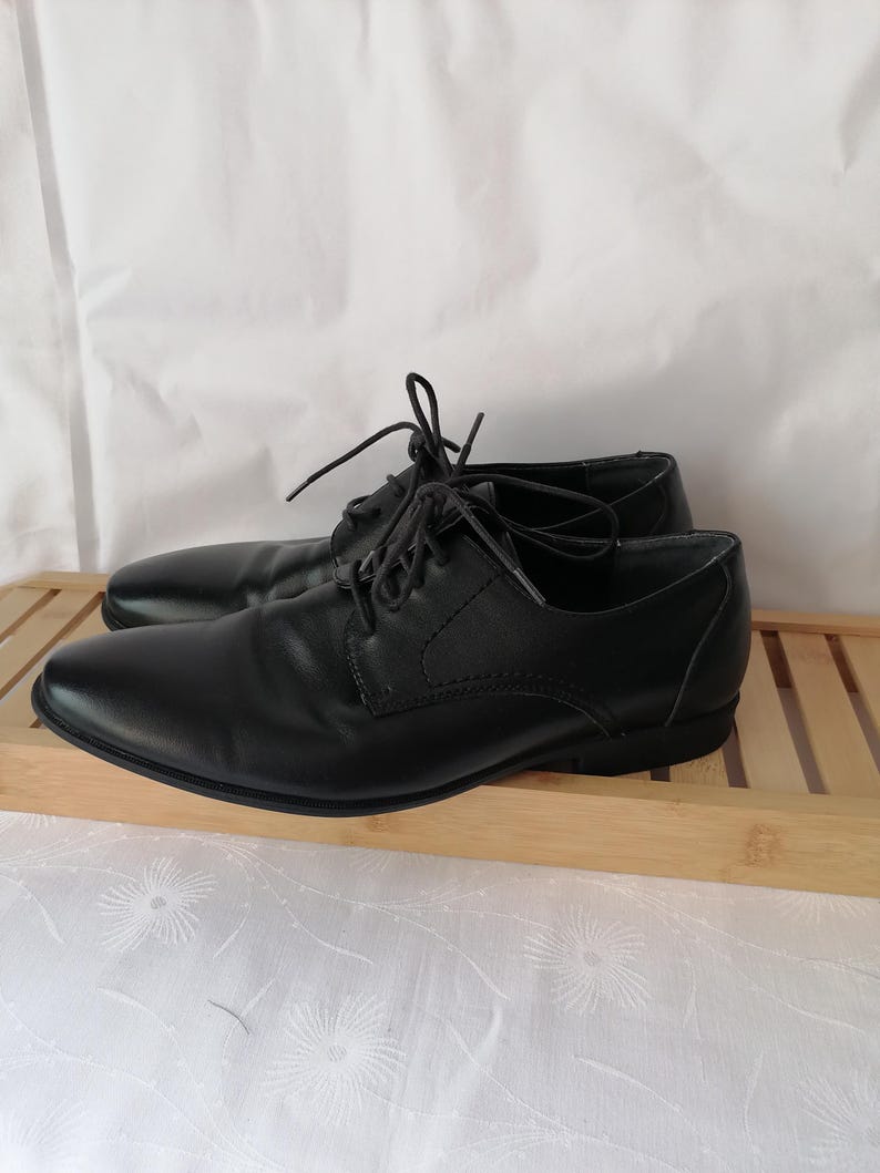 May include: A pair of black leather lace-up shoes with a classic design. The shoes have a rounded toe and a low heel.
