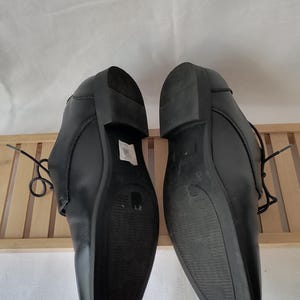 May include: A pair of black leather dress shoes with lace-up closures. The shoes have a pointed toe and a low heel.
