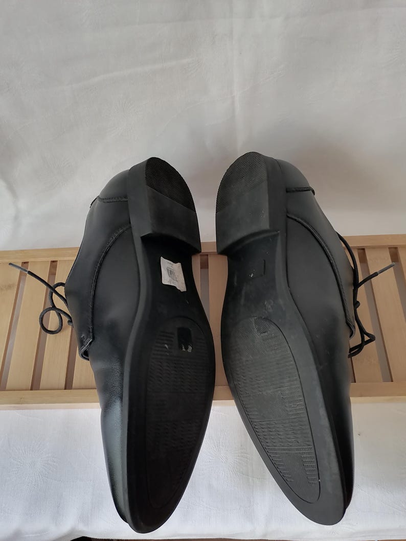 May include: A pair of black leather dress shoes with lace-up closures. The shoes have a pointed toe and a low heel.