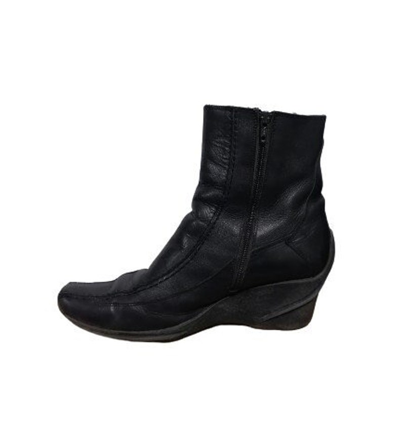 May include: Black leather ankle boots with a wedge heel and a zip on the side.